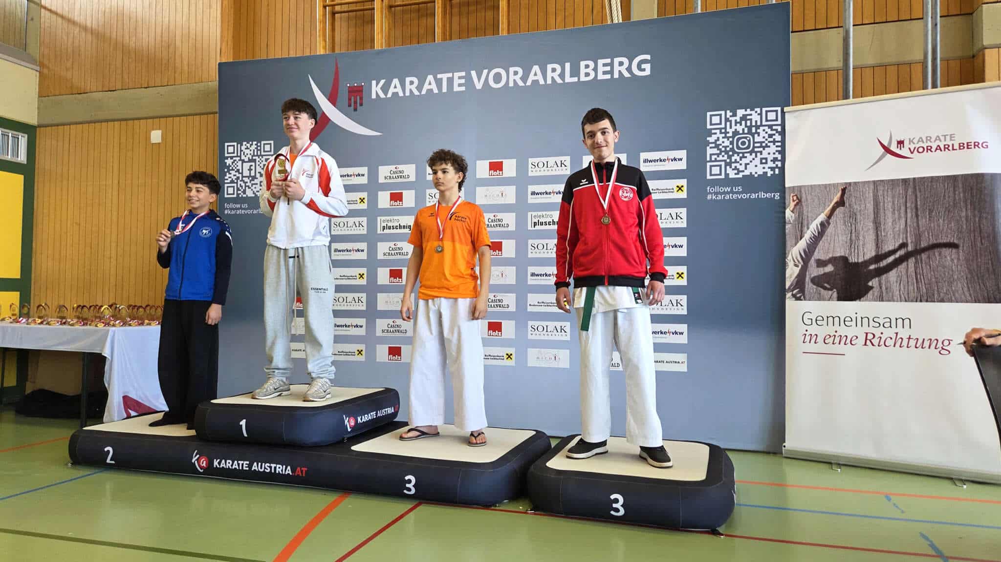 Siegerpodest des Bewerbs Kata Kadetten männlich der Landesmeisterschaft 2026 mit dem Sieger, dem Zweit- und den zwei Drittplatzierten im Trainingsanzug auf dem Siegerpodest