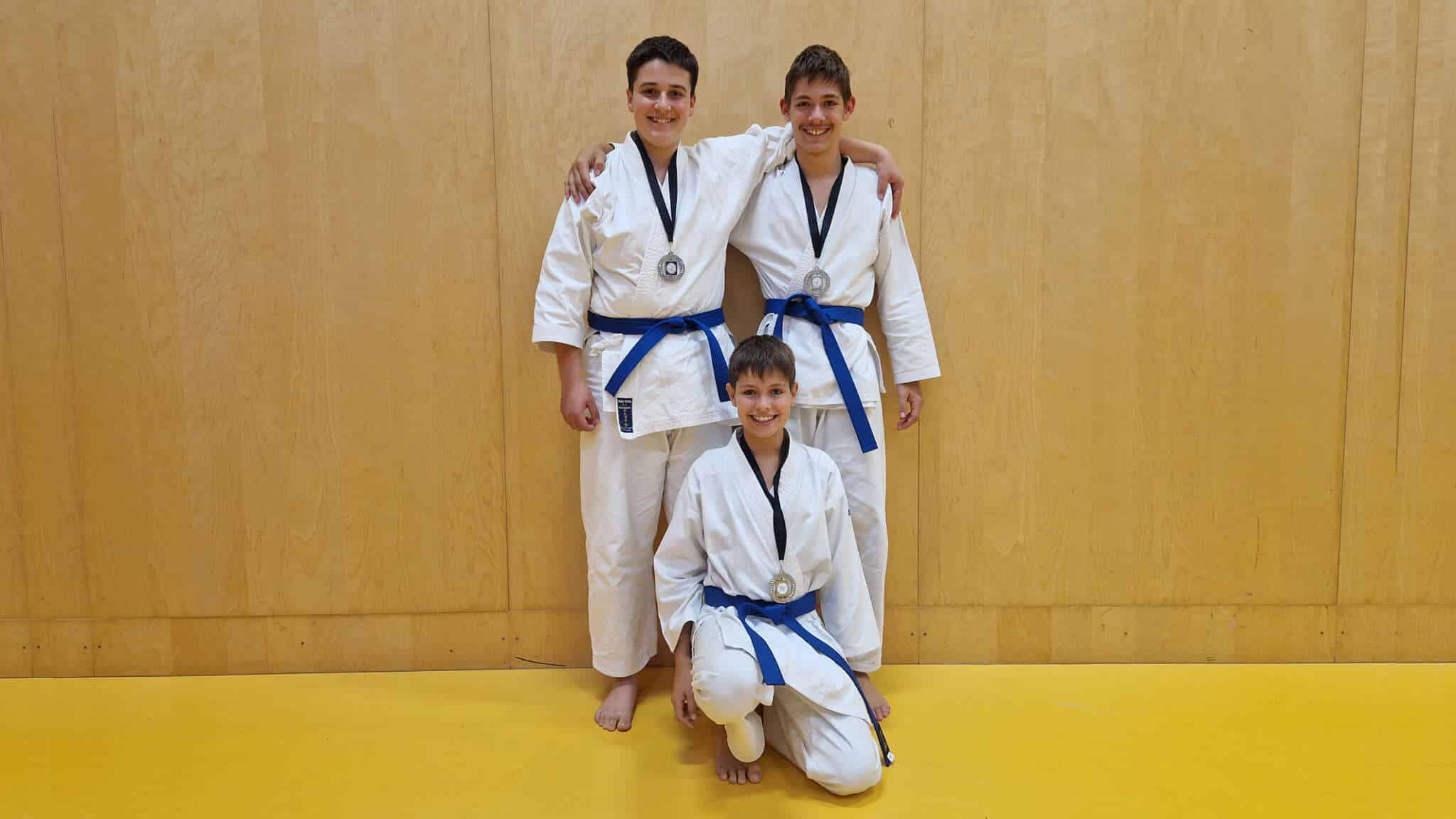 Die drei Bludenzer Karatekas im Gi mit ihren Silbermedaillen in der Halle nach der Siegerehrung.